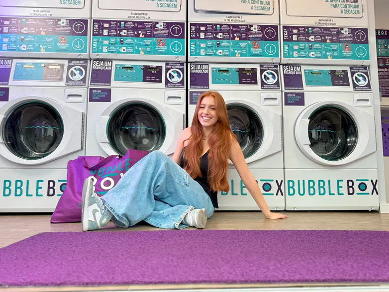 Cliente sentada em frente às máquinas de lavar e secar da Bubble Box